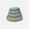 Tiered stack of circular foam pads with blue top layer and speckled brown/multicolor base.